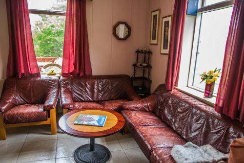 a living room with a leather couch and a table at Korpudalur HI Hostel in Flateyri