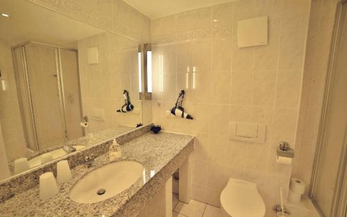 ein Badezimmer mit Waschbecken, Toilette und Spiegel in der Unterkunft Ferienwohnung Binzer Strandgut im Haus Jahreszeiten Binz in Binz