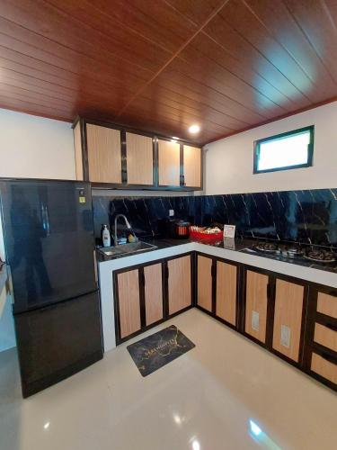 a kitchen with wooden cabinets and a black refrigerator at Yustien Homestay Jogja 3 Bedroom - Private Villa in Bantul