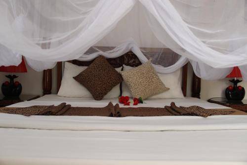 a white bed with pillows and curtains on it at Al-Minar Hotel in Zanzibar City
