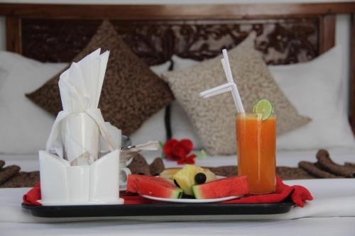 a tray with a plate of fruit and a drink on a bed at Al-Minar Hotel in Zanzibar City