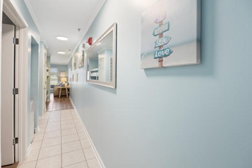 a hallway with white walls and white tile floors at Grand Caribbean West Unit 103W By Pkrm in Pensacola