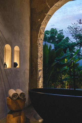 a bathroom with a bath tub and a window at SIVANA, Hotel Boutique with ocean or garden views - Adults only in Uluwatu