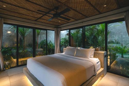 a bedroom with a large bed and large windows at SIVANA, Hotel Boutique with ocean or garden views - Adults only in Uluwatu
