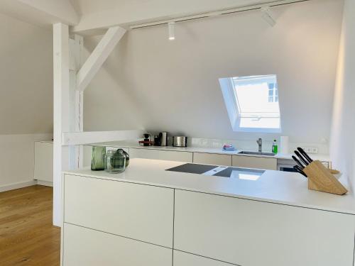 a white kitchen with white cabinets and a window at Ferienwohnung Circus Loft in der Villa Circus Putbus in Putbus