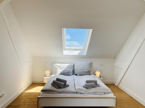 a white bedroom with a bed with a window at Ferienwohnung Circus Loft in der Villa Circus Putbus in Putbus