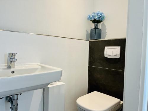 a bathroom with a sink and a toilet and a vase of flowers at Ferienwohnung Circus Loft in der Villa Circus Putbus in Putbus