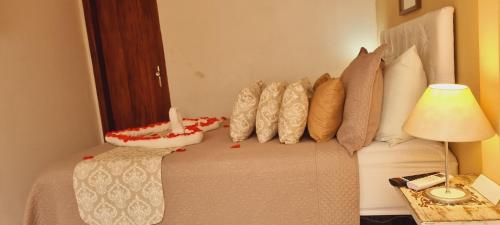 a bedroom with a bed with pillows and a lamp at Pousada Pura vida in Itacaré