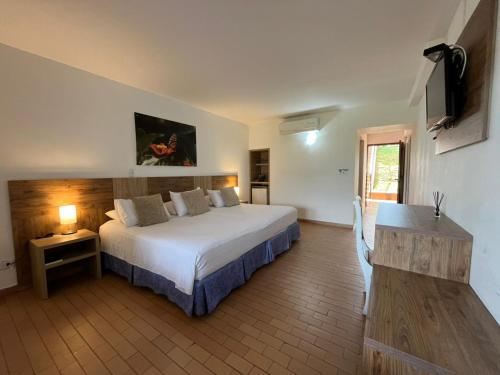 a bedroom with a large white bed and a television at Hotel Los Viñedos in Lemos
