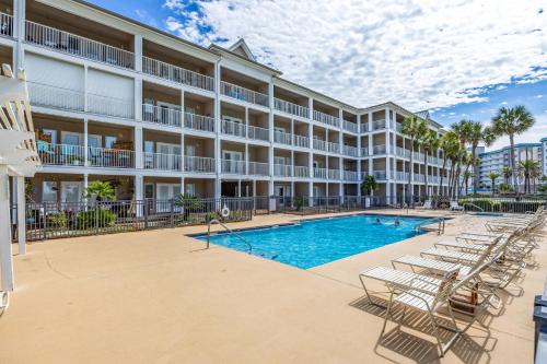 an apartment building with a swimming pool and lounge chairs at Grand Caribbean West Unit 103W By Pkrm in Pensacola