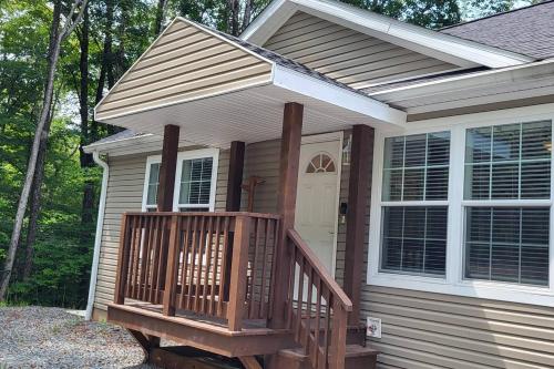 a house with a wooden porch with a white door at Serenity On The Lehigh River in Thornhurst