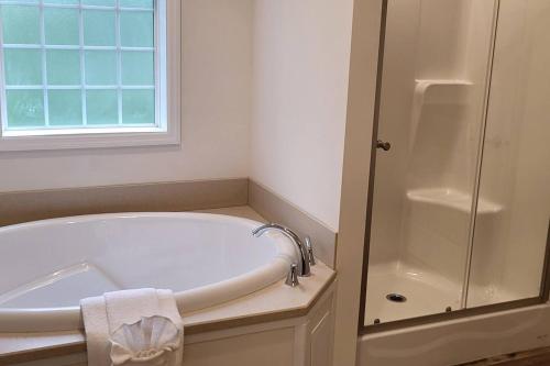 a white bathroom with a tub and a shower at Serenity On The Lehigh River in Thornhurst