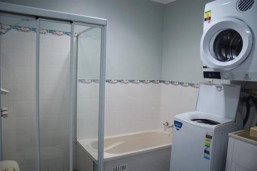 a bathroom with a shower and a washing machine at Paragon Apartment 6 - Bring your own linen. in South West Rocks