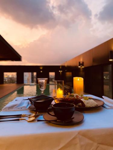 a table with a plate of food and a candle at Zayn Hotel Bangkok - Airport Link Access in Bangkok