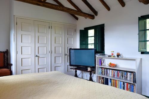a bedroom with a bed and a tv and a book shelf at Alameda Country House in Tenjo