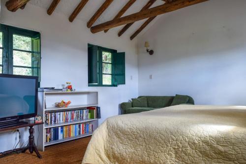 a bedroom with a bed and a tv and a chair at Alameda Country House in Tenjo