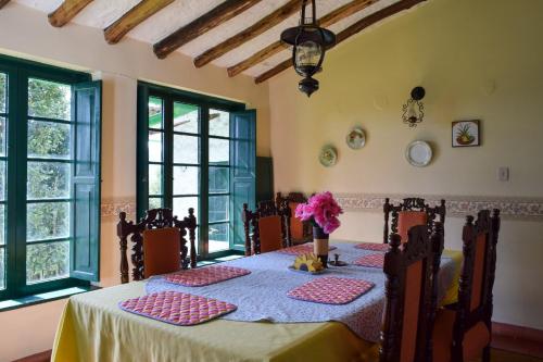 a dining room with a table and chairs and windows at Alameda Country House in Tenjo