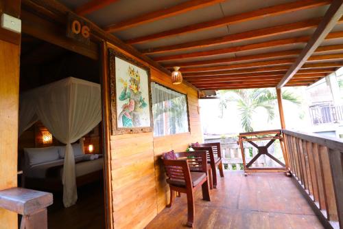 a porch with chairs and a couch on a balcony at Doni House & Villas in Ubud