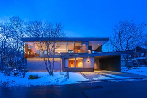 a large house in the snow at night at JADE D Plus and E Plus Hakuba in Hakuba