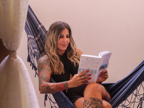 a woman sitting in a hammock reading a book at Pousada Pura vida in Itacaré
