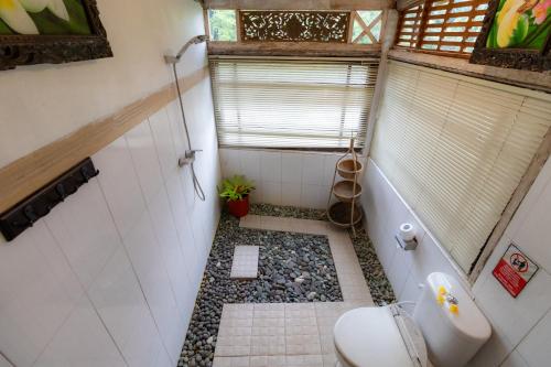 a bathroom with a toilet and a gravel floor at Doni House & Villas in Ubud
