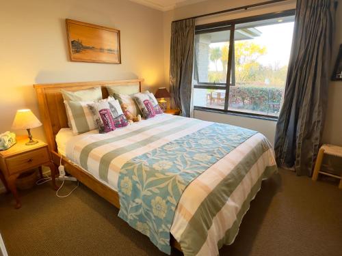 a bedroom with a large bed and a window at Acacia Bay Lodge- Private Manor with Lake and Garden views in Taupo