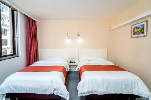 two beds in a room with red curtains at LN Whitehouse Hotel in Guangzhou