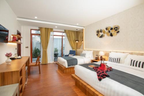 a hotel room with two beds and a desk at Cambana La Rivière Hotel in Battambang
