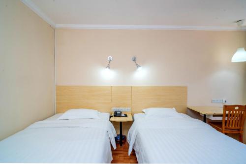 two beds in a room with a table and a desk at LN Whitehouse Hotel in Guangzhou
