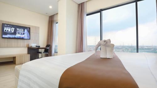a hotel room with a large bed and a tv at Vasaka Hotel Jakarta Managed by Dafam in Jakarta