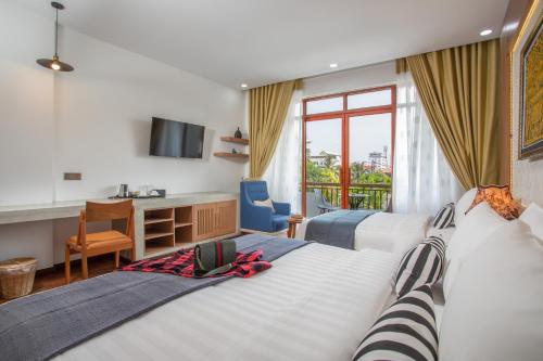 a hotel room with two beds and a desk at Cambana La Rivière Hotel in Battambang