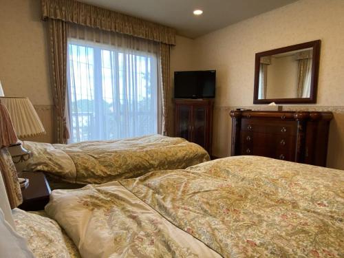a hotel room with two beds and a mirror at Atami Venus in Atami