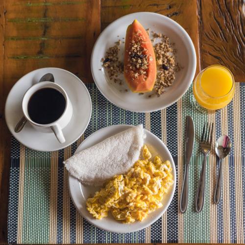 a table with two plates of food and a cup of coffee at Casa Dela Pousada in Cabo Frio