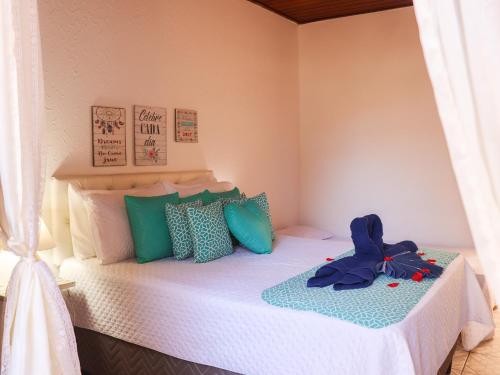 a bedroom with a white bed with blue and green pillows at Pousada Pura vida in Itacaré