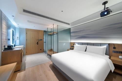 a bedroom with a large white bed and a bathroom at Qiuguo Hotel Chongqing Guanyin Bridge Branch in Chongqing
