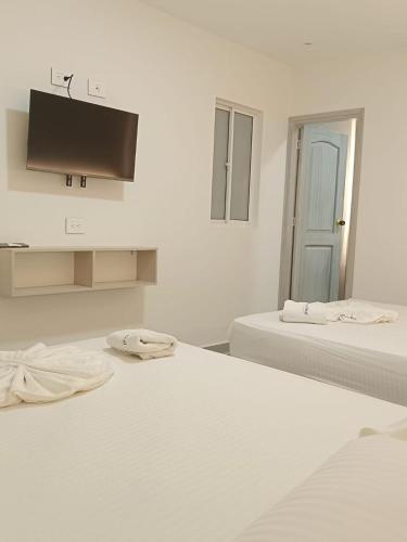 a white room with two beds and a flat screen tv at Hotel San Sebastian Real in Cartagena de Indias