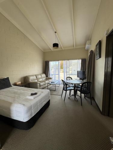 a hotel room with a bed and a table and chairs at Fountain Court Motel in Tauranga