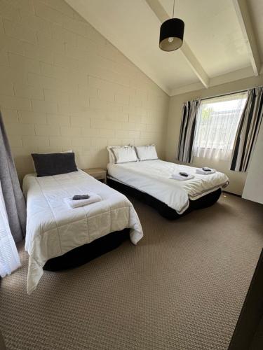 a bedroom with two beds and a window at Fountain Court Motel in Tauranga