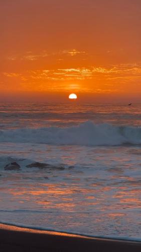 a sunset on the beach with the sun in the horizon at Casa Olas, Refugio Costero in Curanipe