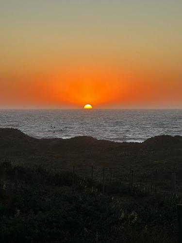 a sunset over the ocean with the sun in the horizon at Casa Olas, Refugio Costero in Curanipe
