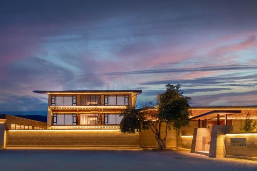 a large building with a sunset in the background at 丽思漫 心宿穹庐四野供氧庄园 in Shangri-La
