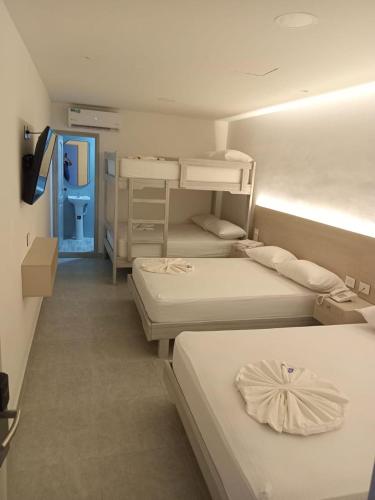 a room with three beds and a blue door at Hotel San Sebastian Real in Cartagena de Indias