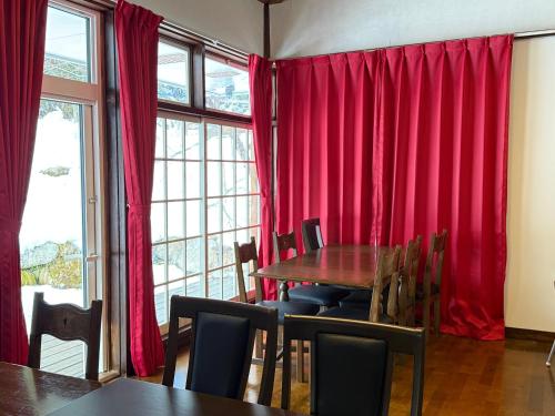 a dining room with red curtains and a table and chairs at Hotel Junior Mint Hakuba in Hakuba