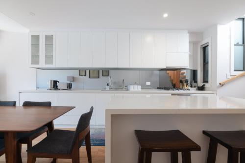 a kitchen with white cabinets and a table and chairs at Modern Home in Erskineville w AC and Parking in Sydney