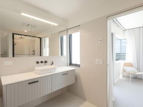 Un baño blanco con lavabo y espejo. en Salt at East, en Port Fairy