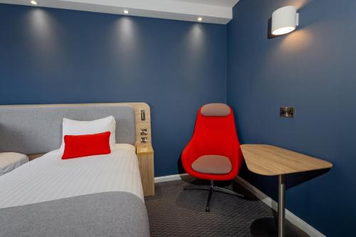 a bedroom with a red chair and a bed and a desk at Holiday Inn Express Norwich by IHG in Norwich