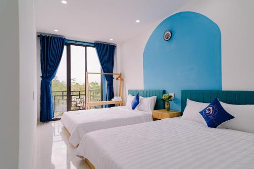 2 letti in una camera con pareti e finestre blu di Pao Homestay a Hue