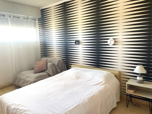 une chambre avec un lit blanc et une chaise dans l'établissement La Grande Motte: Appart 2 pers, Clim, Parking - FR-1-790-33, à La Grande Motte