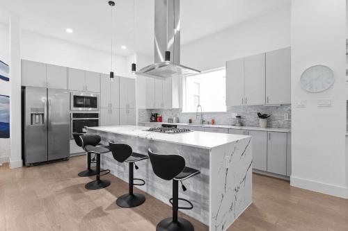 a white kitchen with a large island with bar stools at Spacious Houston 3Bed3 Bath Family Townhome in Houston