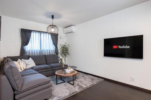 a living room with a couch and a tv on a wall at SWEET VILLA HAKU Tengachaya in Osaka